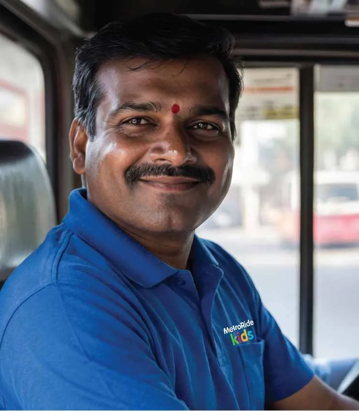 A smiling MetroRide Kids driver in uniform at the wheel